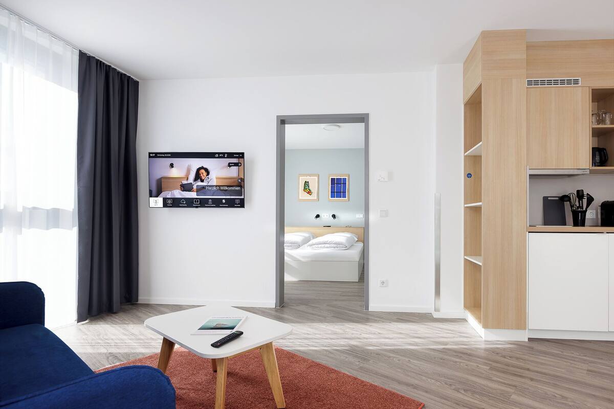 Une chambre d’hôtel moderne équipée d’un lit, d’une télévision, d’un bureau et d’une kitchenette.
