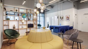 A modern interior with a round seating area, a bookshelf, and a reception desk. - smartments Frankfurt Airport (Frankfurt)