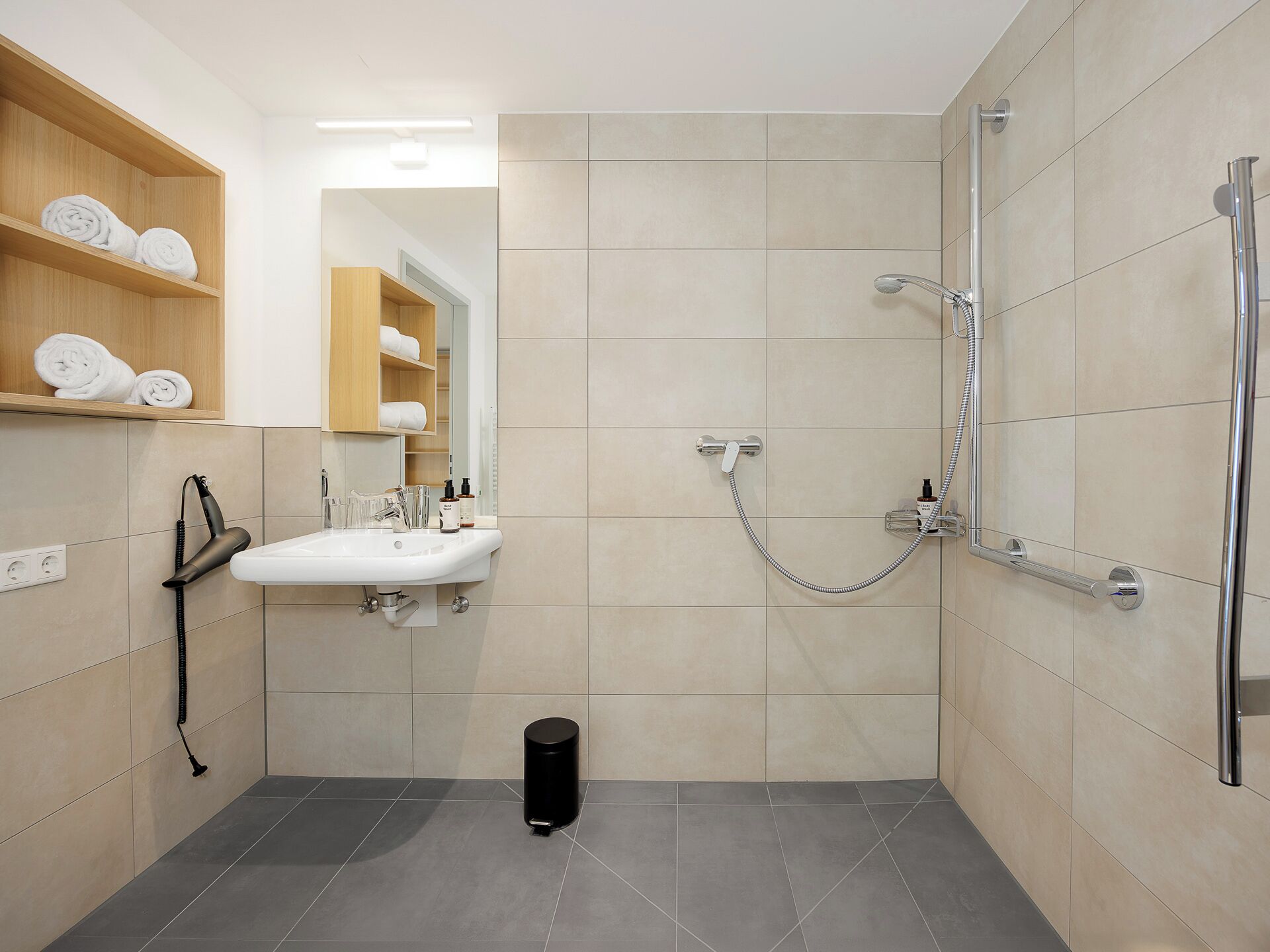 A modern bathroom with a shower, sink, and towel storage.