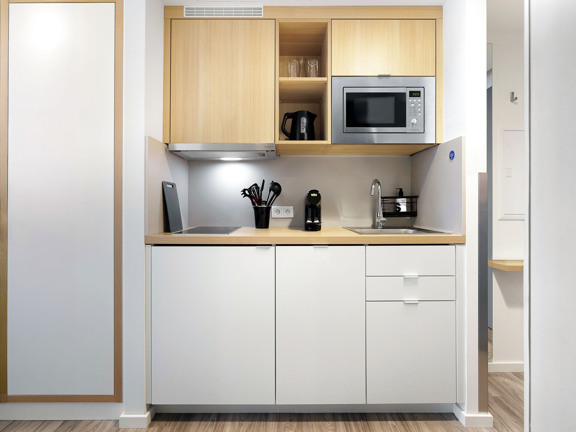 A compact kitchen with a microwave, coffee maker, and a knife block.
