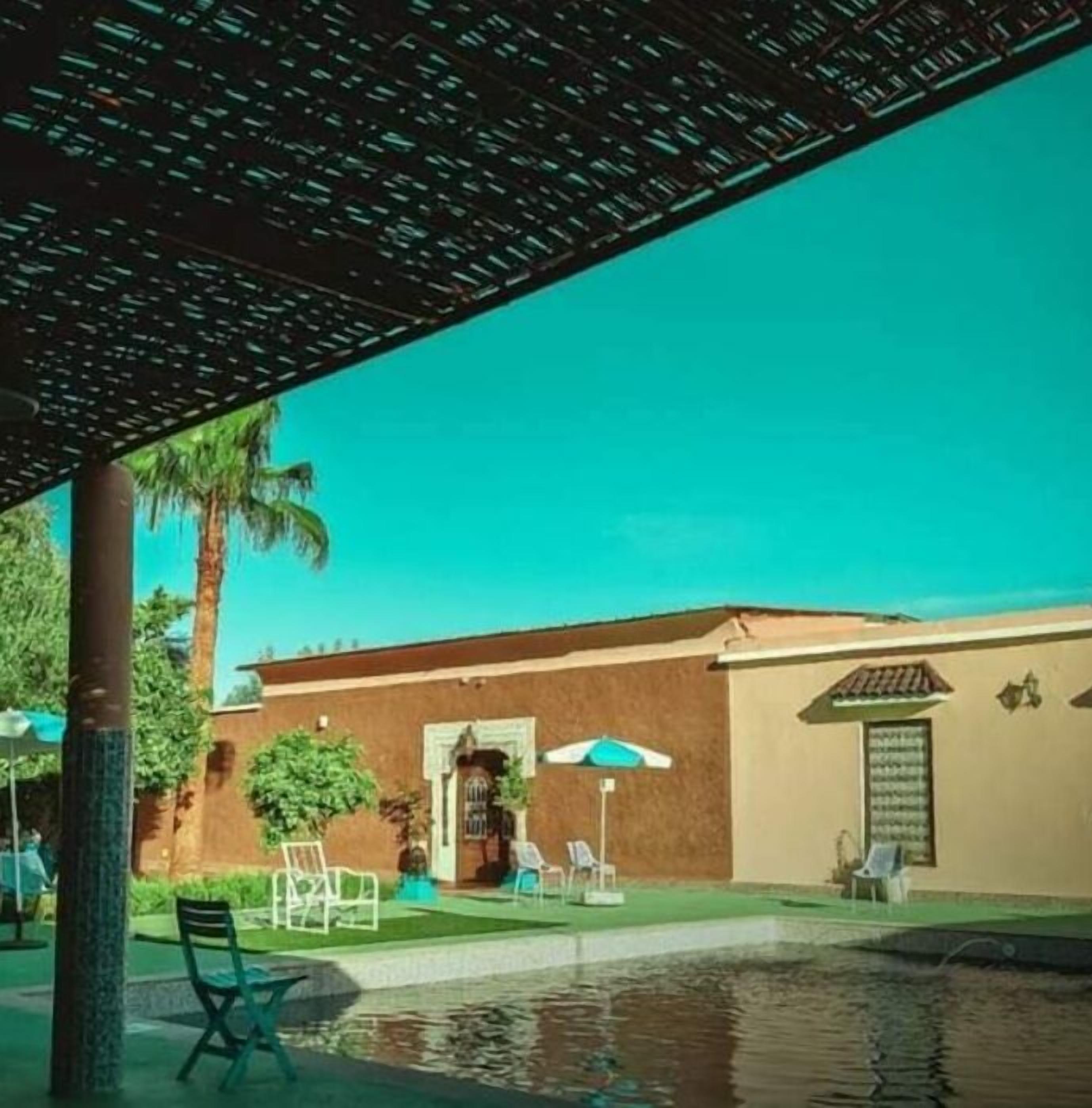 A pool area with a pergola, palm trees, and outdoor seating.