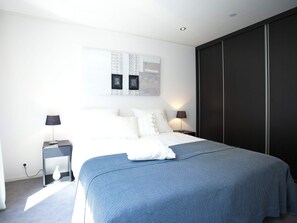 A modern bedroom with a large bed, two bedside tables, and a dark wardrobe. - Modern Holiday Home Near the Golf Course (Velsen-Zuid)