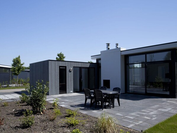 A modern building with a patio area featuring a table and chairs. - Modern Holiday Home Near the Golf Course (Velsen-Zuid)