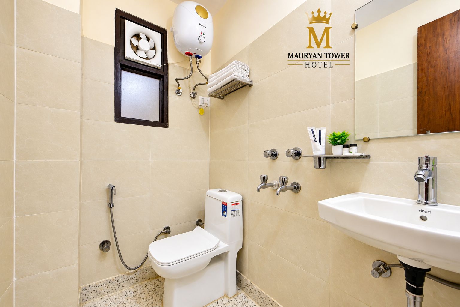 A bathroom with a toilet, bidet, and sink, with a showerhead and towel rack.