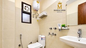 Un baño con inodoro, bidé y lavamanos, con cabezal de ducha y toallero.