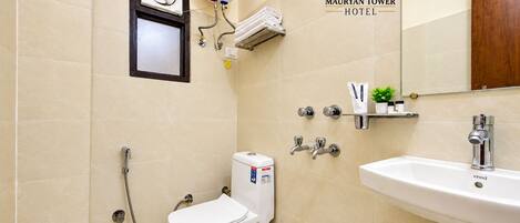 A bathroom with a toilet, bidet, and sink, with a showerhead and towel rack.