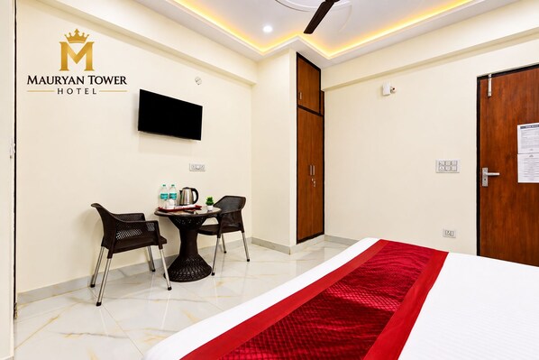 A hotel room with a bed, a TV, a table with chairs, and a red runner. - Mauryan Tower, Yashobhoomi (New Delhi)
