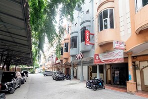 A street lined with parked cars and motorcycles, a building with a sign reading "OYO" and another sign for "Lion Parcel". - Hotel O Metropolitan Homestay Near Komplek Asia Megamas Medan (Medan)