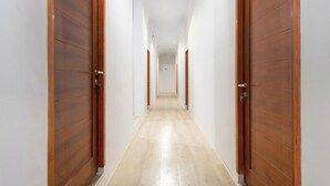 Un pasillo con puertas de madera a ambos lados, que conduce a una habitación al final.