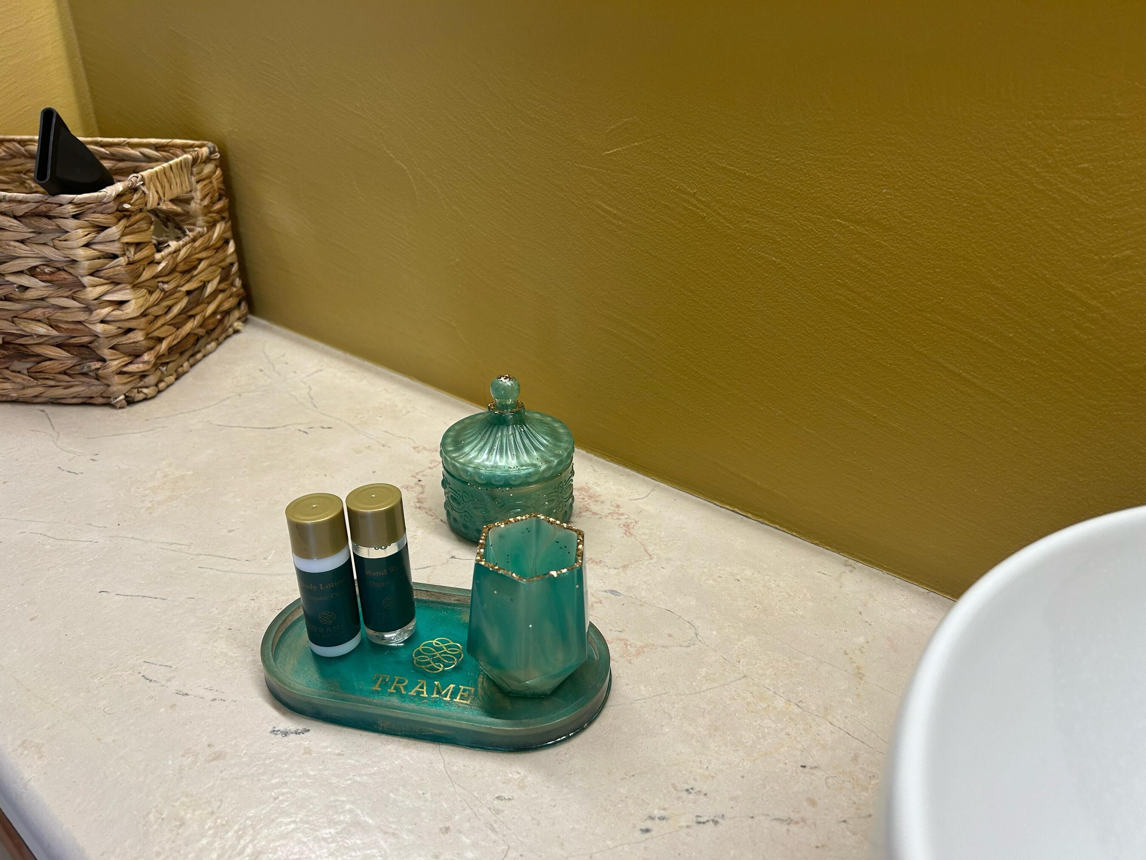 Un mobile bagno con un vassoio verde che contiene due flaconi di lozione e un bicchiere.