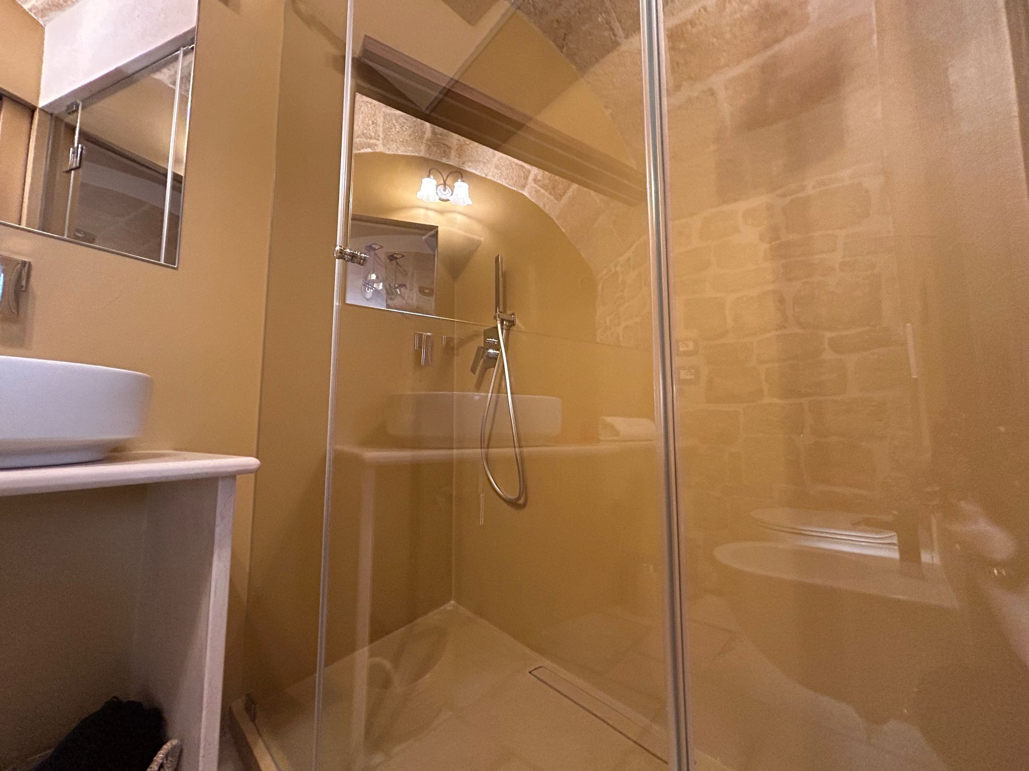 A modern bathroom with a glass-enclosed shower, a white sink, and a mirror above the sink.