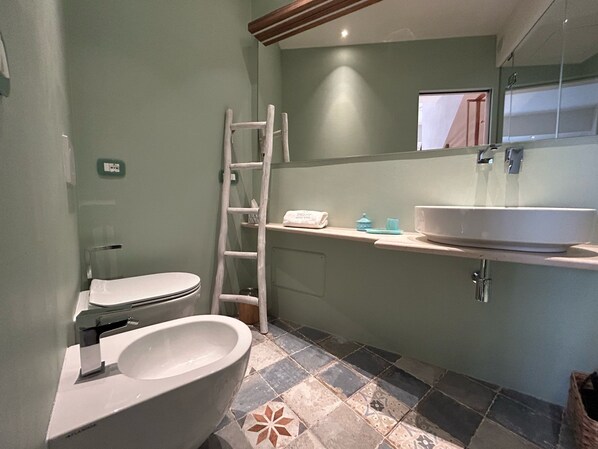 A bathroom with a toilet, bidet, and a large sink.