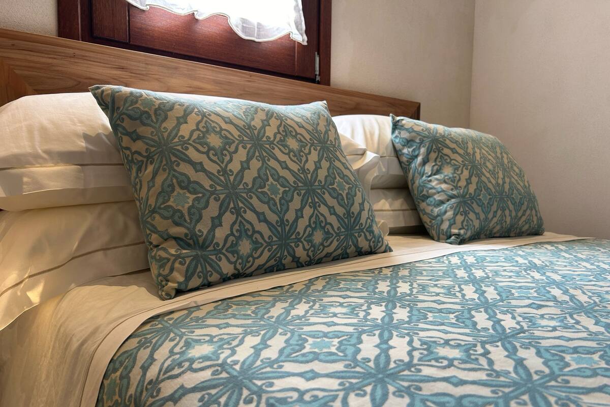 A neatly made bed with patterned pillows and a matching bedspread.