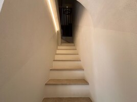 Uma escadaria com corrimão no lado esquerdo e interior escuro visível no topo.