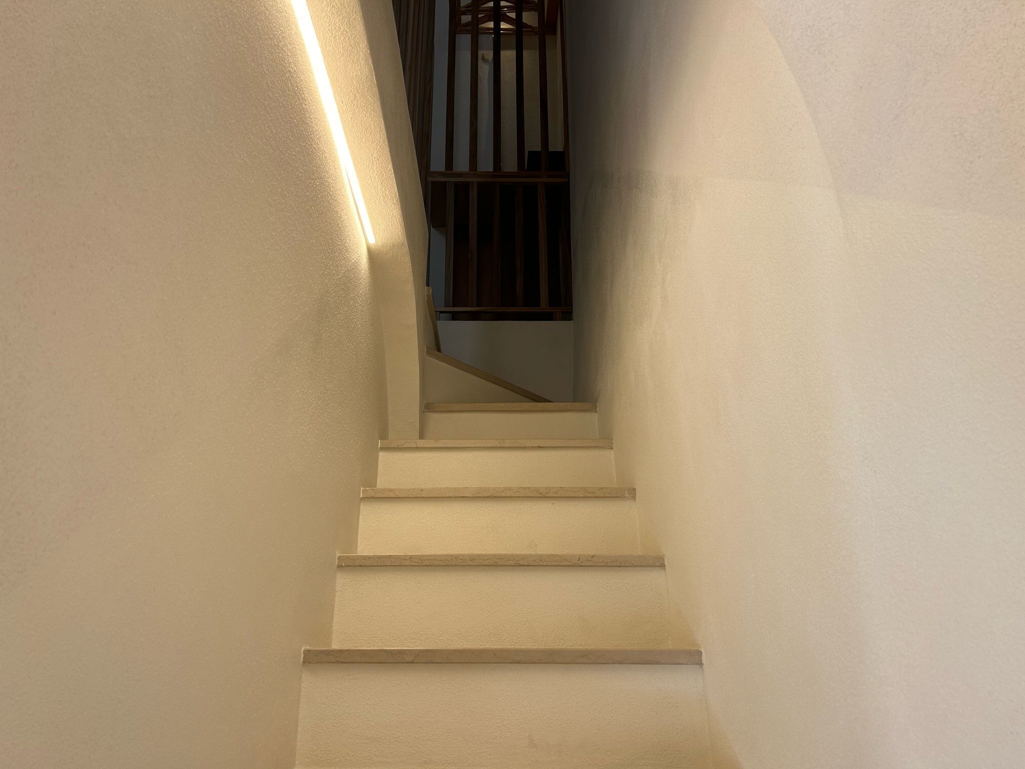 A staircase with a handrail and a light strip on the wall.