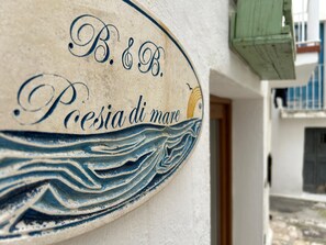 Un letrero con 'B&B' y 'Poesia di mare' sobre una pared texturizada.