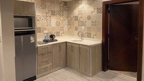 A compact kitchen with a built-in microwave, a refrigerator, and a sink. - GLAMOUR INN - جلامور ان (Madinah)
