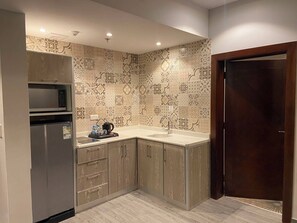 A compact kitchen with a built-in microwave, a refrigerator, and a sink. - GLAMOUR INN - جلامور ان (Madinah)