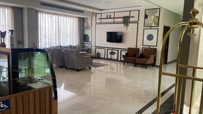 Una sala de estar moderna con sofá, sillones, televisor de pantalla plana y una partici ón de vidrio.