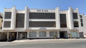 A modern building with a large central window and a sign for 'Holiday Plus Company' below it. - GLAMOUR INN - جلامور ان (Madinah)