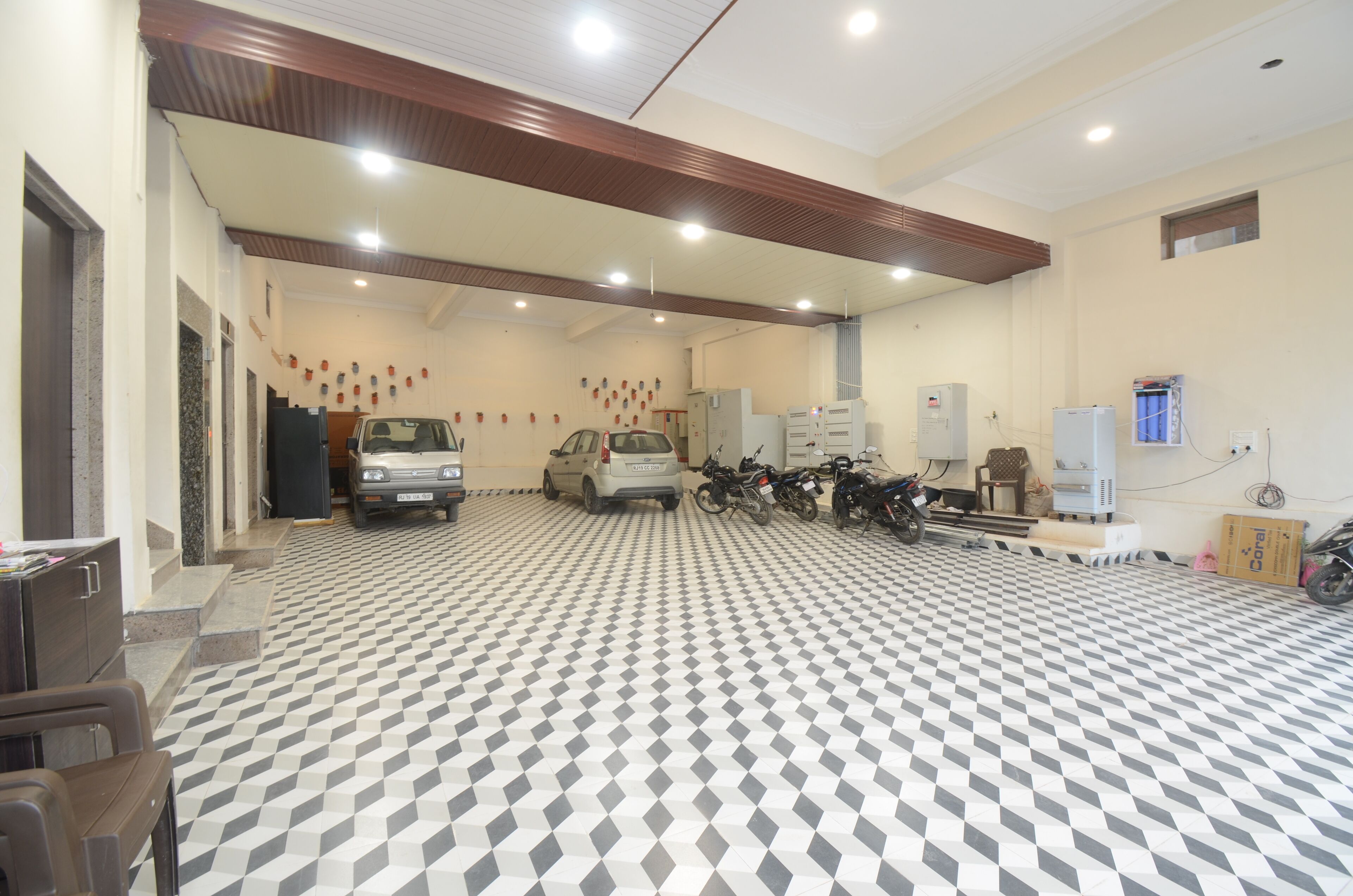A spacious indoor area with a checkered floor, a car, motorcycles, and various appliances.