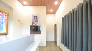 A reception area with a counter, a framed picture, a wall-mounted TV, and a row of curtains. - Hotel Shri Dhwaja Inn (Nathdwara)