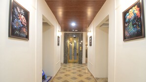 A hallway with patterned flooring, framed artwork on the walls, and a door at the end. - Hotel Shri Dhwaja Inn (Nathdwara)