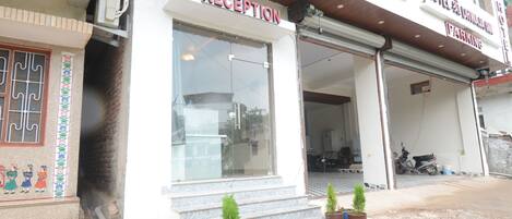 A hotel reception with a clear entrance, steps, and potted plants.