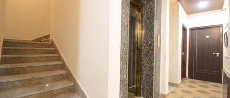 A staircase leading to an elevator, a door, and a patterned floor.