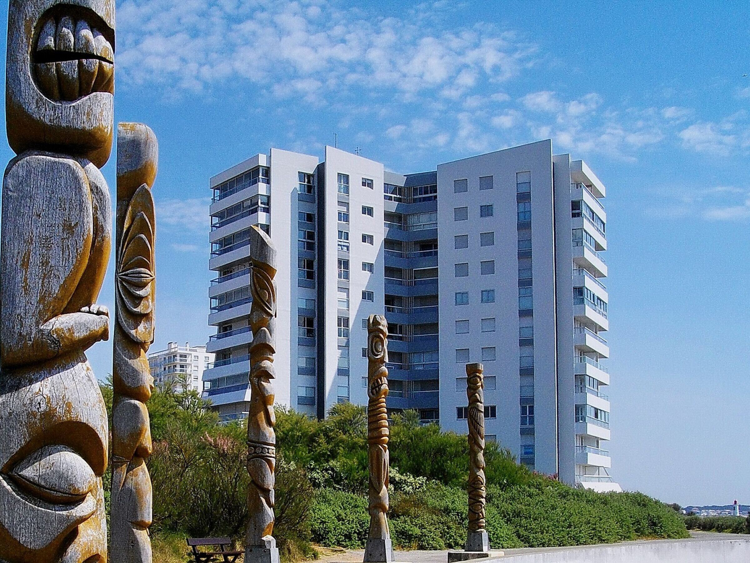 A modern high-rise building with multiple balconies and a clear sky.