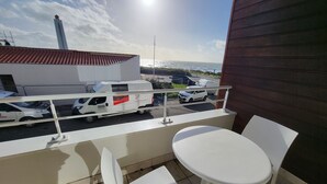 A balcony with a white table and chairs, overlooking a parking area with several cars and a van. - Seaview Apartment with Balcony, 2 Bedrooms, Parking, Close to Beaches & Shops (Les Sables-d'Olonne)