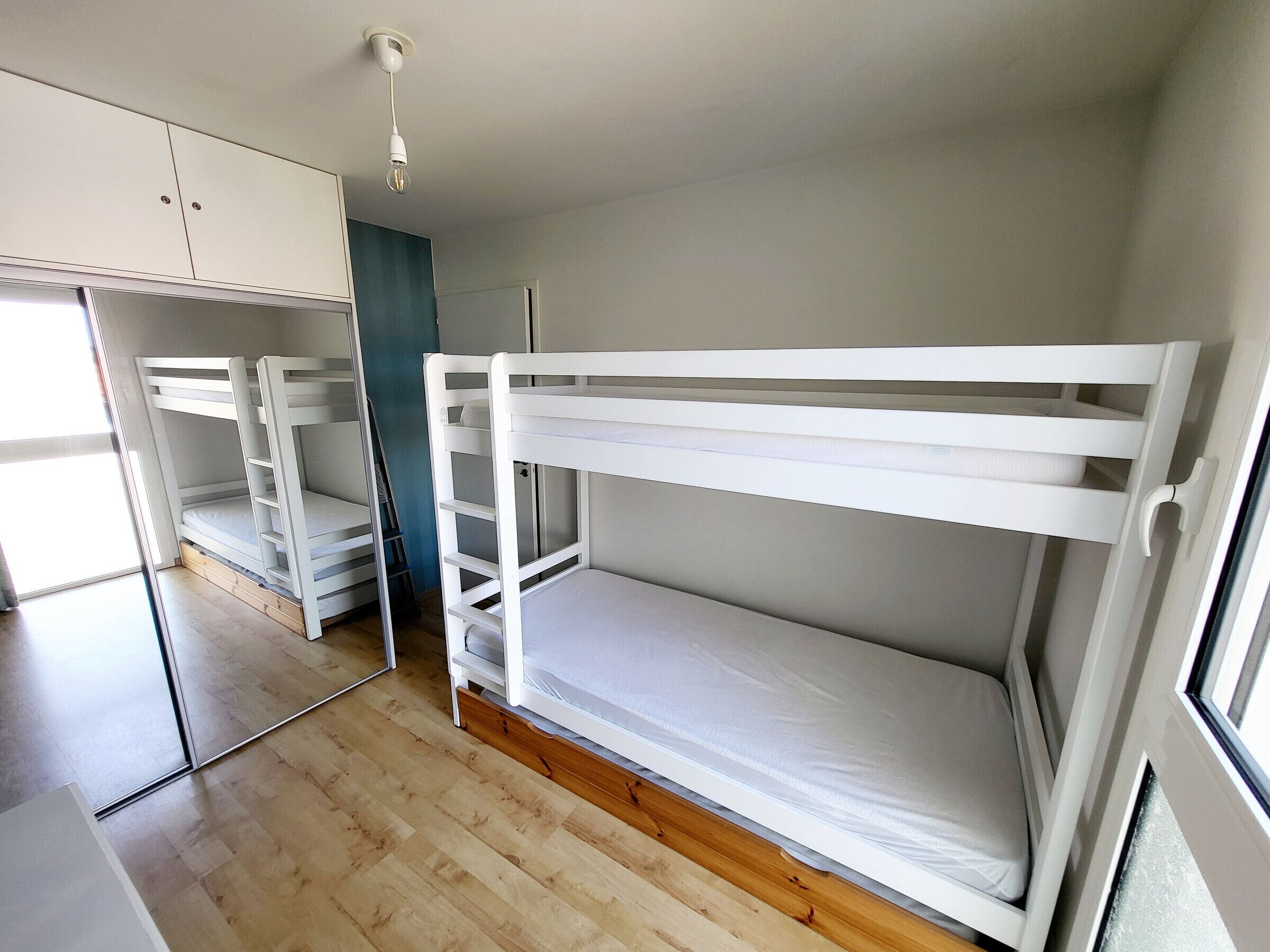 A room with bunk beds, a wardrobe, and a mirror.