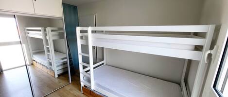 A room with bunk beds, a wardrobe, and a mirror.