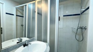 A bathroom with a white sink, a mirror, and a shower area. - Charming Apartment Steps from Capellans Beach – Free WiFi, Fully Equipped Kitchen, Sleeps 4 (Salou)