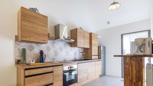 Eine moderne Küche mit Holzschnitzereien, einem eingebauten Ofen und einer Kaffeemaschine.