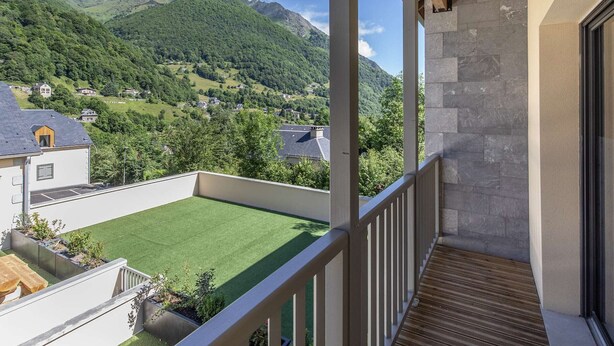 Ein Balkon mit Blick auf eine grüne Wiese und Berge.