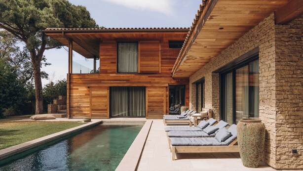 Ett modernt hus med en swimmingpool, ett trädäck och stenväggar.