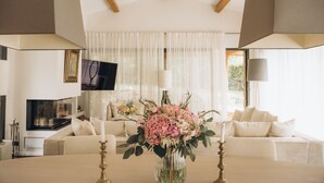 Ett modernt vardagsrum med en öppen spis, en tv och en stor blomsteruppsättning på ett bord.