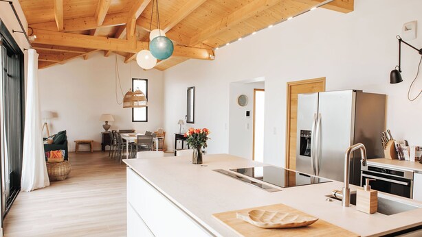 Una cocina moderna con una isla grande, electrodomésticos de acero inoxidable y techo de madera.