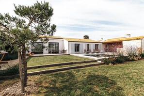 A modern house with a well-maintained lawn, outdoor seating area, and a swimming pool.