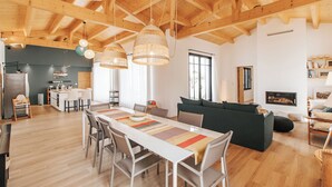 Un salón amplio con techo de madera alto, una mesa de comedor con sillas, un sofá y una chimenea.
