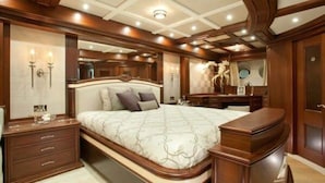 Un dormitorio lujoso con una cama grande, cabecera de madera, mesitas de noche y un tocador con espejo.