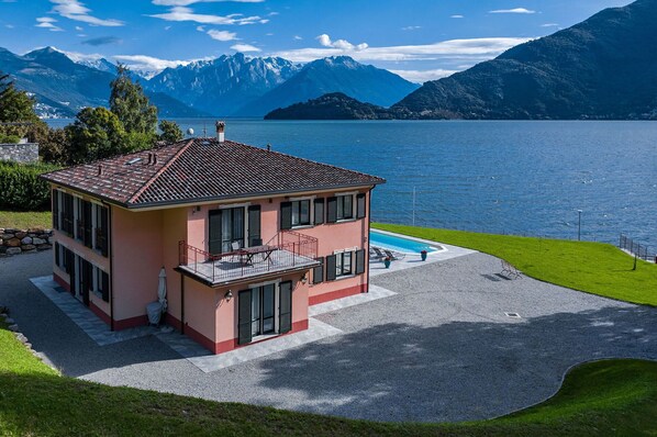 Ein zweistöckiges Haus mit Balkon, Schwimmbad und Blick auf See und Berge.