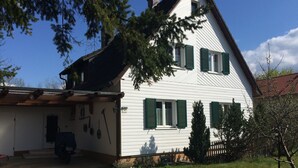 Une maison à deux étages avec un garage, des volets verts et une pelouse bien entretenue.
