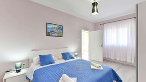 A bedroom with a bed, a nightstand, a lamp, a painting, and a window with curtains. - Holiday home Beata (Posedarje)
