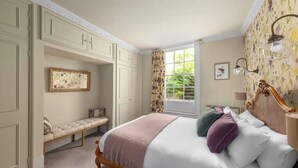 A bedroom with a bed, a bench, a window, and a wall-mounted lamp. - 3-bedroom Georgian maisonette (Bath and North East Somerset)
