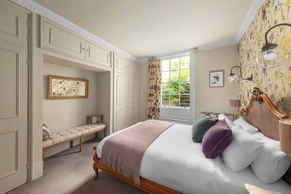 Une chambre à coucher comprenant un lit, un banc, une fenêtre et une lampe fixée au mur.