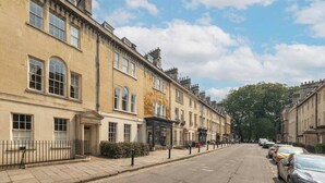 A row of traditional terraced houses with uniform architecture, a clear street, and parked cars. - 3-bedroom Georgian maisonette (Bath and North East Somerset)
