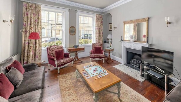 A living room with a sofa, armchairs, a coffee table, a fireplace, and a television. - 3-bedroom Georgian maisonette (Bath and North East Somerset)