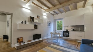 Een moderne keuken met witte kasten, een ingebouwde oven en een eethoek met een glazen tafel en stoelen.